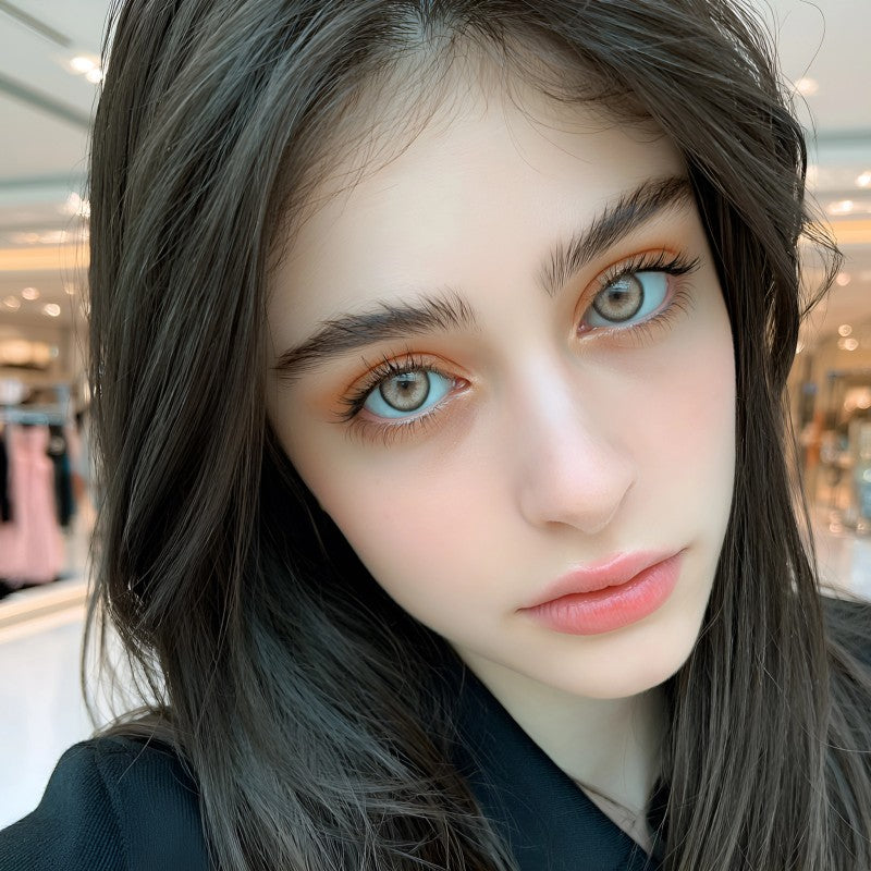 Beautiful female model with dark hair wearing MIIEMO Smoky Ash natural gray contact lenses