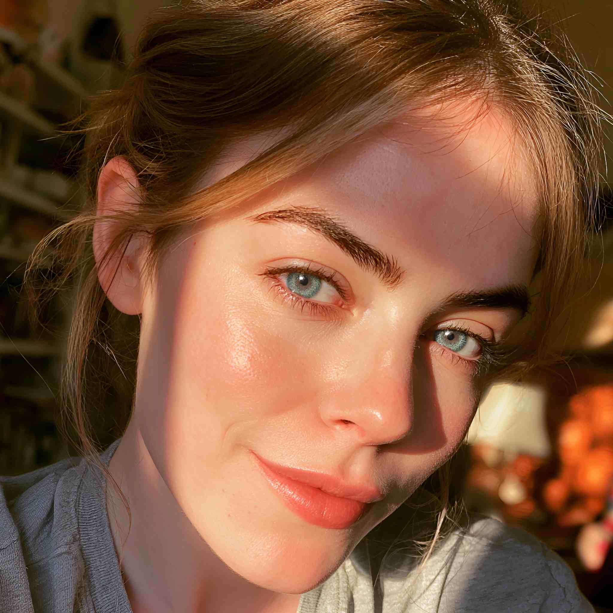 Beautiful blonde female model with natural freckles in warm sunlight wearing MIIEMO Sapphire Blue contact lenses