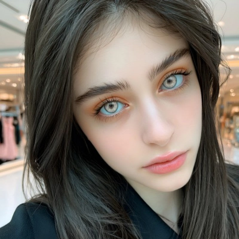 Gorgeous dark haired female model with striking aesthetic makeup wearing MIIEMO Natural Grey 6 month wear grey contacts